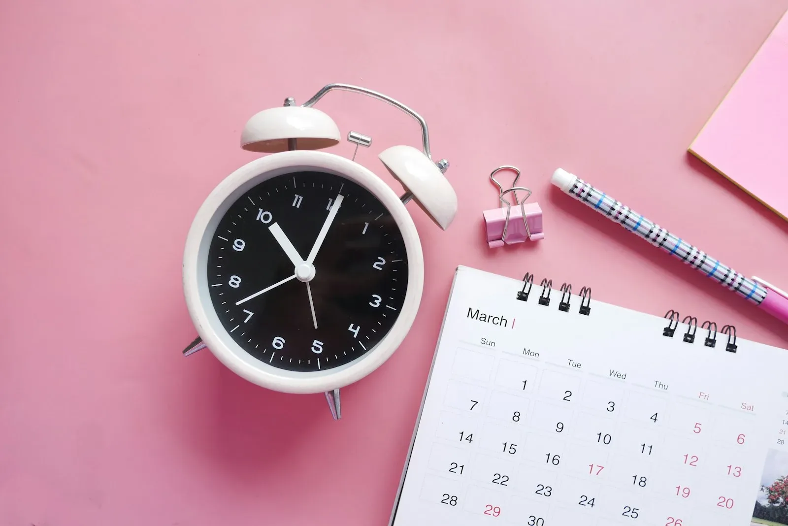 Relógio despertador ao lado de um calendário