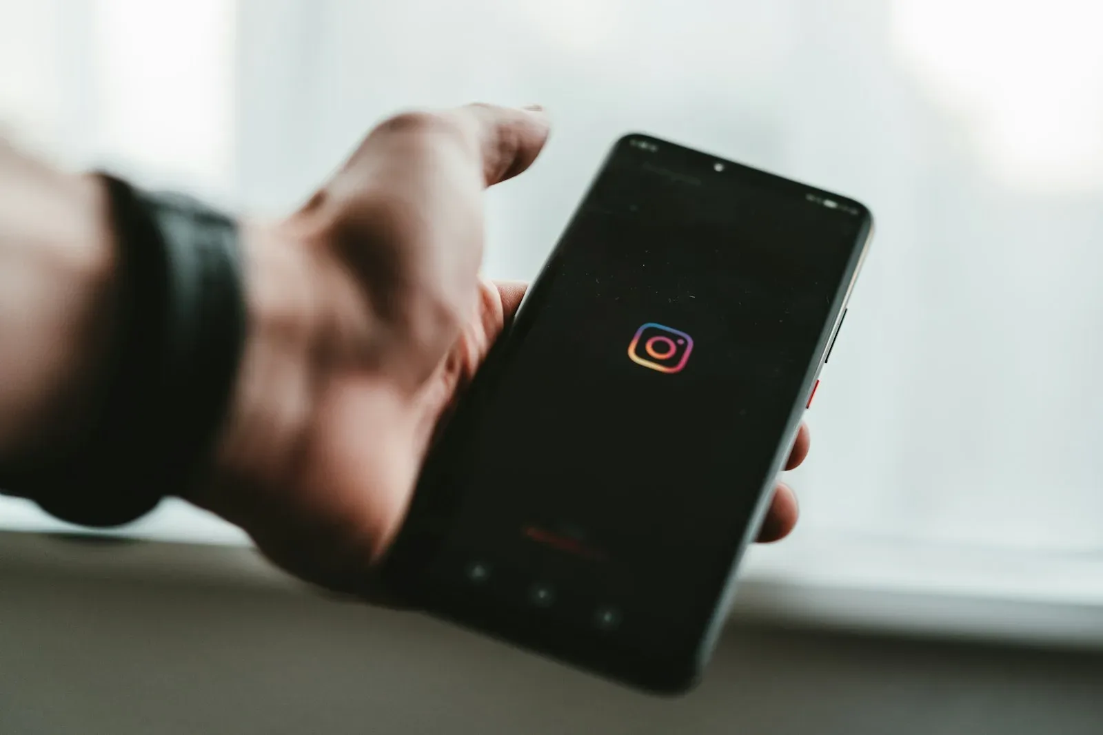 Mão segurando um smartphone com a tela apagada